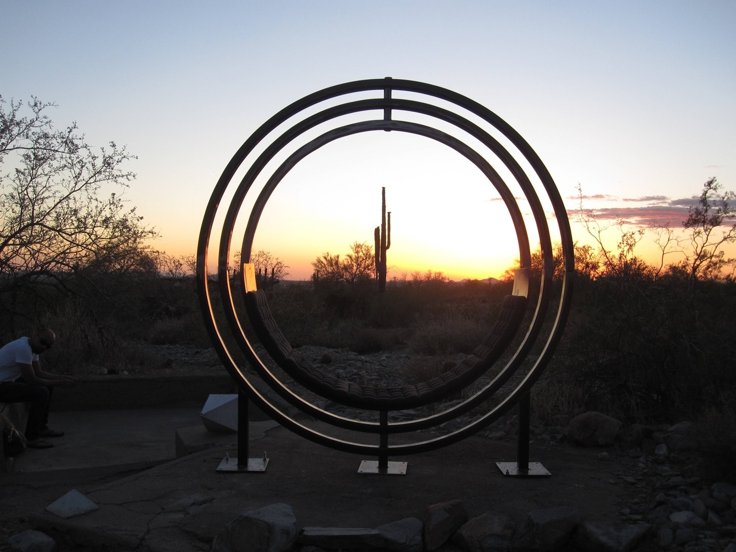 Circular swing sculpture overlooking desert sunset